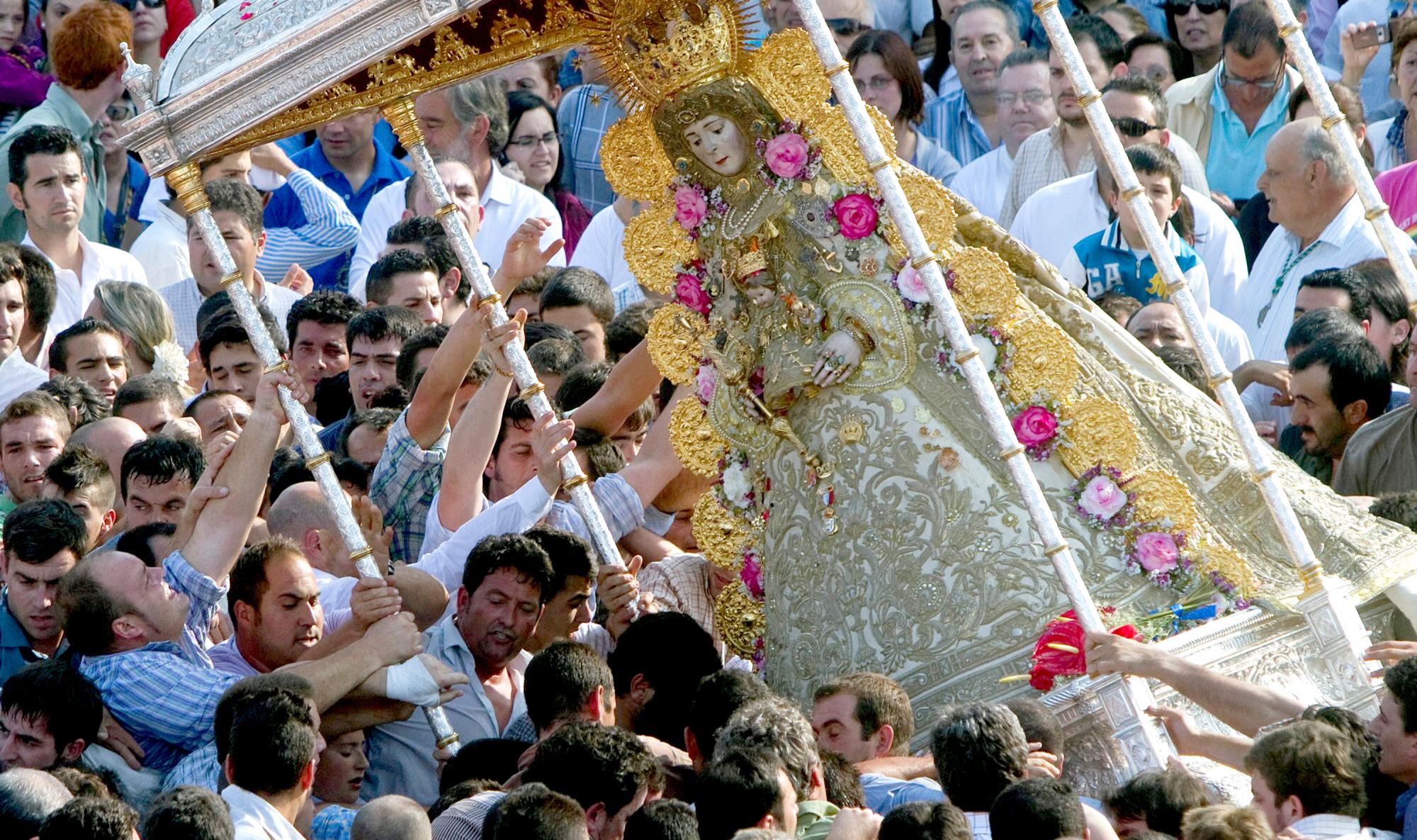 El Rocio-i Madonna Andalúzia pünkösdi körmenet és zarándoklat Spanyolországban.Emberek ünnepi körmenetben egy díszes, virágokkal borított szobrot visznek. Tarka ruhák, emelkedett hangulat, napsütéses nap.