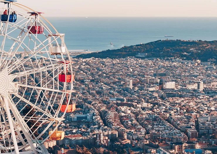Tibidabo retro vidámpark. Óriáskerék színes kabinokkal balra, háttérben városkép és tengerpanoráma. Nyugodt, derűs hangulat.