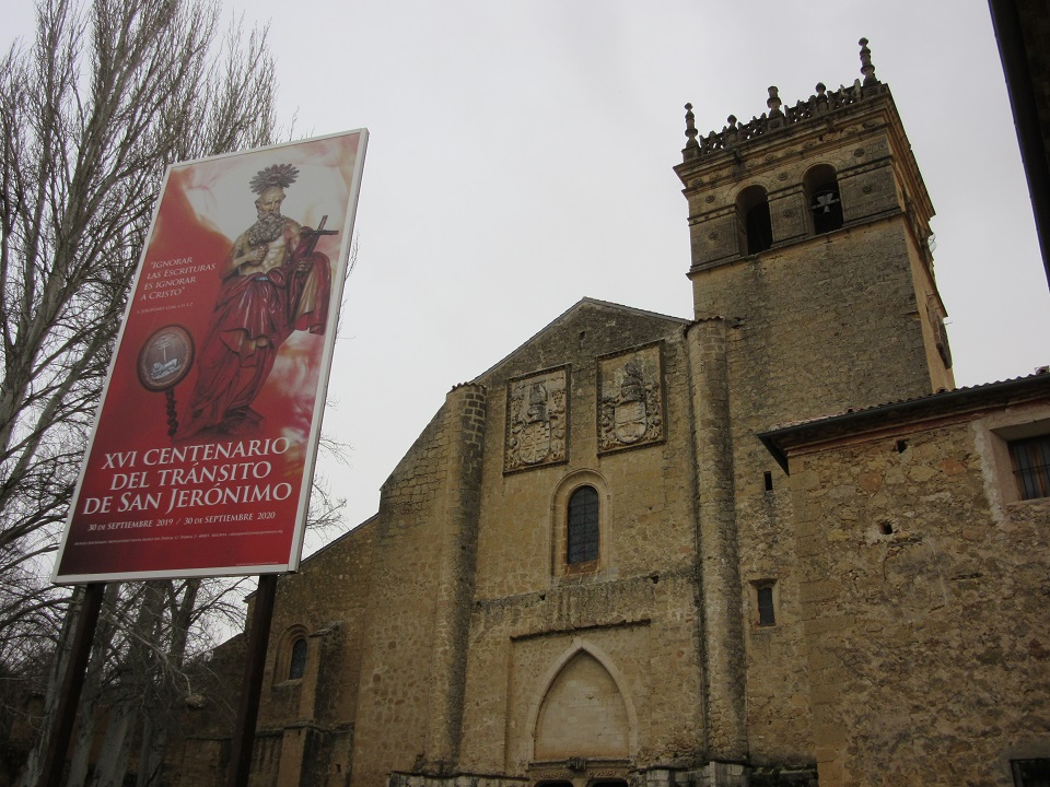 Segovia Jeromosok templom épülete szürke téli időben, előtte egy jubileumi zászló