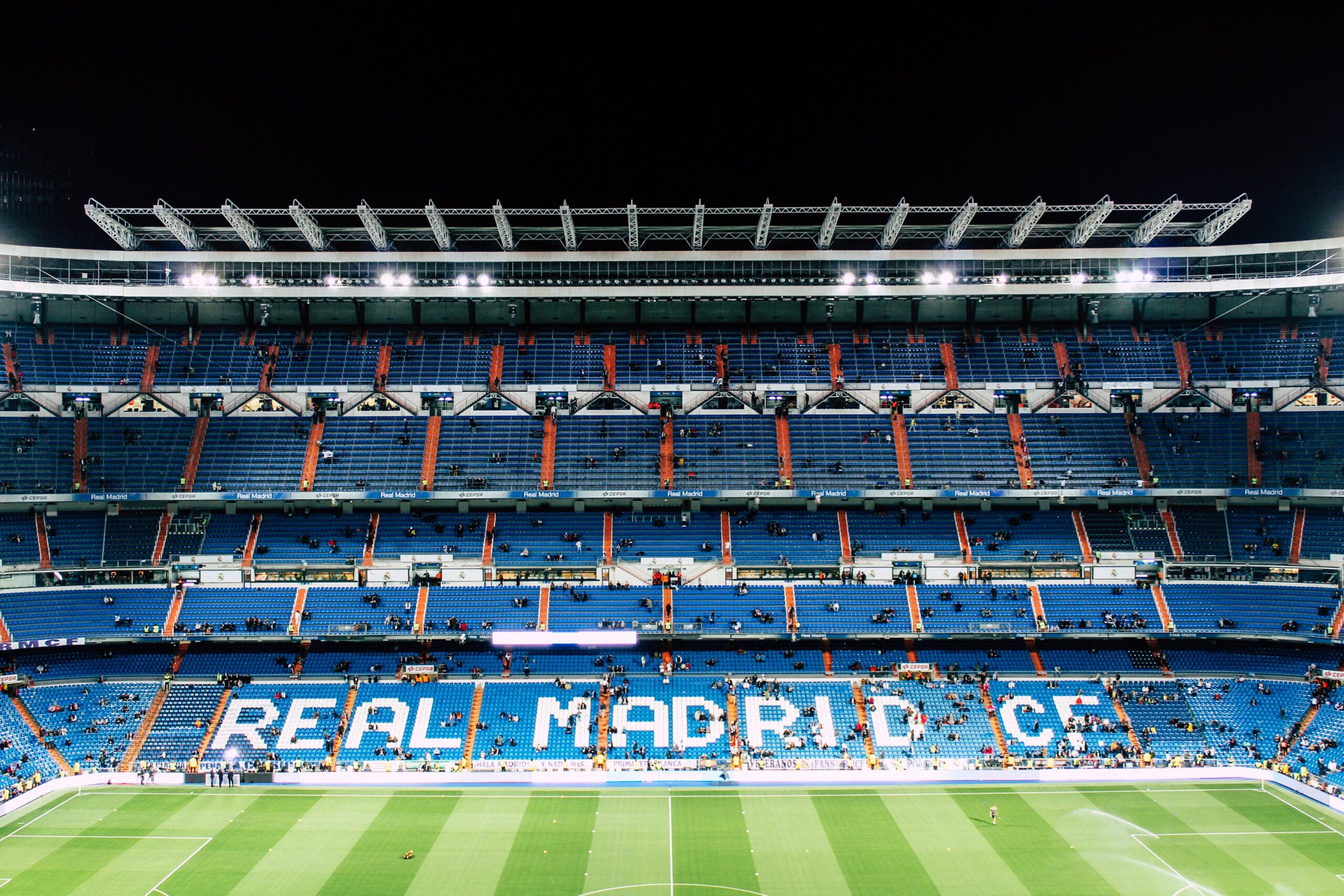 Bernabeú Futballstadion sok üres kék székkel, középen "REAL MADRID C.F." felirattal. Este, világít a reflektor, kevés ember látható.