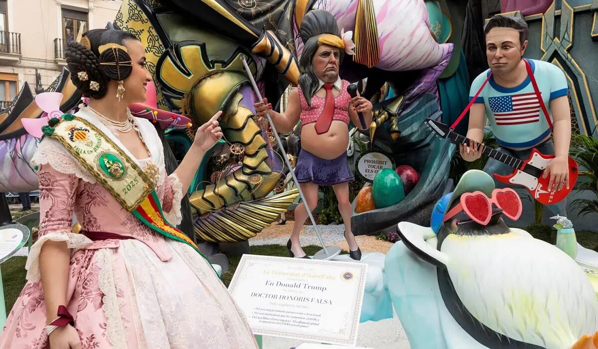 Las fallas, Valencia ünnepén,, karneváli bábuk egy színes, utcai kiállításon. Egy nő díszes ruhában figyel egy mikrofonos bábúra. A háttérben bábú gitárral.
