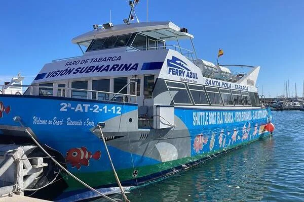 Santa Pola hajókirándulás katamaránnal Tabarca szigetre. Kék-fehér komphajó dokk mellett, oldalán halak képeivel és felirattal. Feliratok: "Visión Submarina", "Ferry Azul", napos idő.