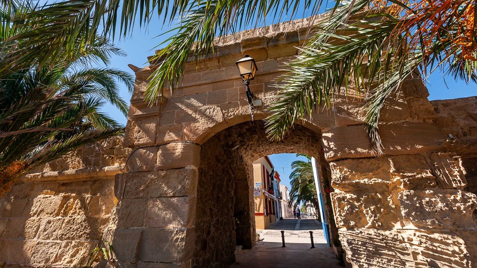 A tabarcai Puerta de San Rafael városkapuja, amely ősi hangulatot áraszt napfényes pálmafák ölelésében.