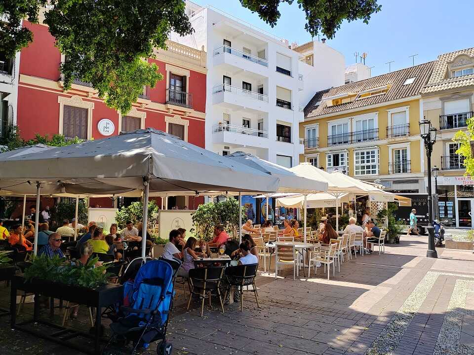 Fuengirola egyik hangulatos tere, kávézókkal, bárakkal, árnyékolók alatt emberek ülnek és beszélgetnek