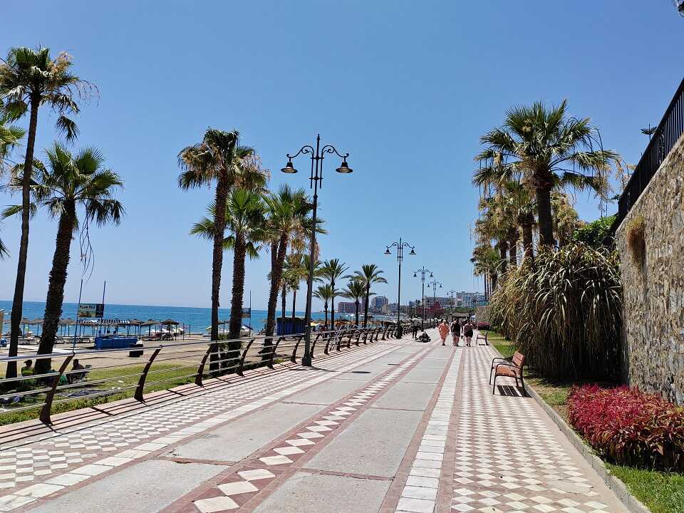 Benalmádena tengerpart sétány pálmafákkal és piros virággokkal, kék ég