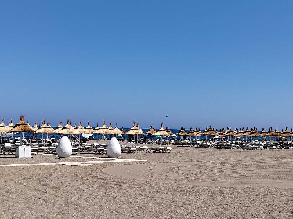 Torremolinos tengerpart, napozóágyakkal, napernyővel, kék ég, és finom homokos part